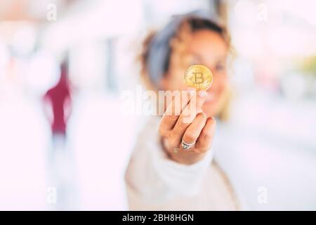 Cheerful modern caucasian woman in business world showing a gold bitcoin cryptocurrency for blockchain commerce trading concept for virtual money and new technology era Stock Photo