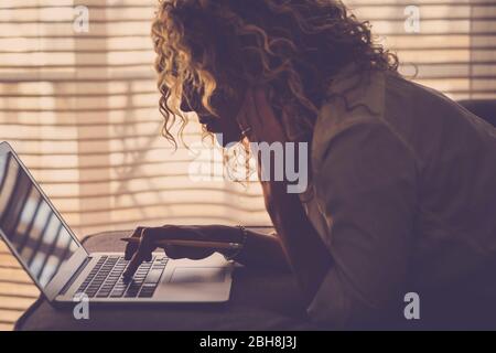 Woman lay down at home on the sofa working with a computer laptop and internet - alterative office for modern manager concept- use of technology for people - housewife at work Stock Photo