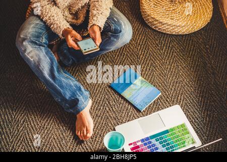 Technology and modern devices phone and laptop concept with woman using cellular and notebook on the floor at home - people internet social addicted or at work out of office in freelance free mode Stock Photo
