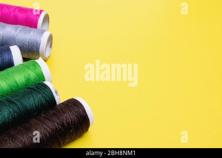 Coils with multicolored threads on yellow background Stock Photo