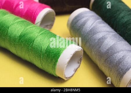 Coils with multicolored threads on yellow background Stock Photo
