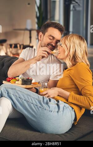 Happy married people eating together on the sofa Stock Photo