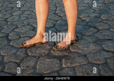 Legs of mature woman in dirty that stands on dry bottom of salty estuary Stock Photo