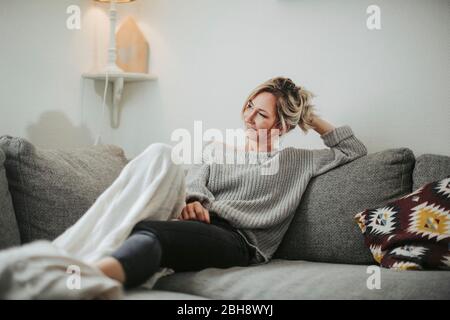 Frau sitzt entspannt auf der Couch