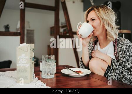 Frau am Frühstückstisch, fröhlich, Kaffee trinken Stock Photo