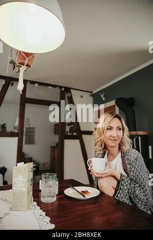 Frau am Frühstückstisch, fröhlich, Kaffee trinken Stock Photo