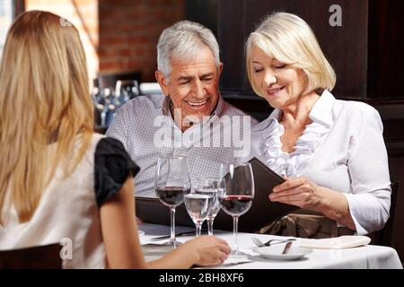 A happy couple of seniors are looking at the menu in the restaurant together Stock Photo