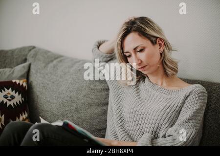 Frau mit Zeitschrift auf der Couch Stock Photo