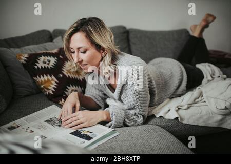 Frau mit Zeitschrift auf der Couch Stock Photo