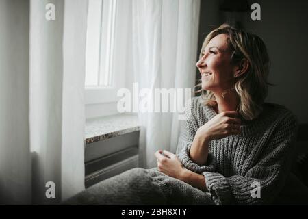Frau blickt freudig aus dem Fenster Stock Photo