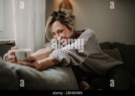 Frau mit Teetasse auf der Couch
