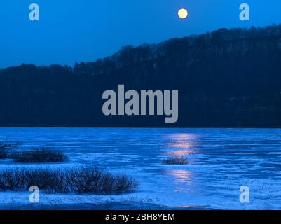 Europa, Deutschland, Hessen, Vöhl, Nationalpark Kellerwald-Edersee, Winterabend am vereisten Edersee, Vollmond, Spiegelung Stock Photo