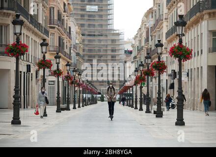 A man wearing a face mask riding on a Segway along an empty Marques de Larios street amid the coronavirus outbreak disease COVID-19.Following the confinement decreed by the Spanish government and to be extend until 10th May, an exceptional situation of unusual urban scenes such as empty streets or bars, restaurants and shops closed has been caused. Stock Photo