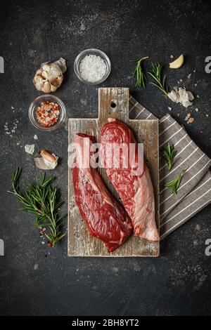 Raw Fresh Steak Sirloin Flap Served with Rosemary, garlic and spices on Wooden cutting Board. Black Angus Beef Meat. Top View Stock Photo