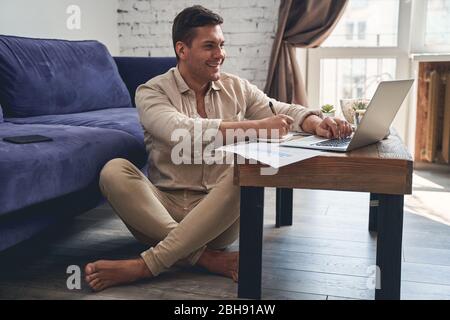 Pleased man sitting cross-legged on the floor Stock Photo