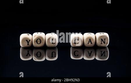 wooden blocks with the text you can on a black background Stock Photo