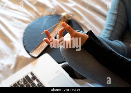 Woman doing yoga with the computer and incense. Stock Photo