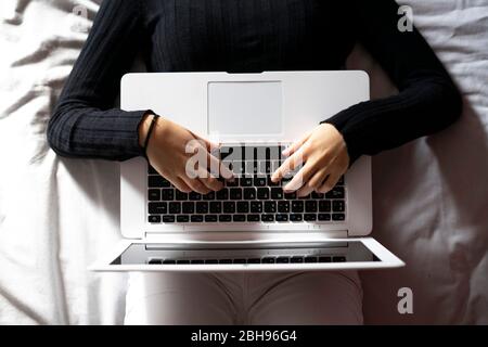 Woman working with the laptop in bed. Stock Photo