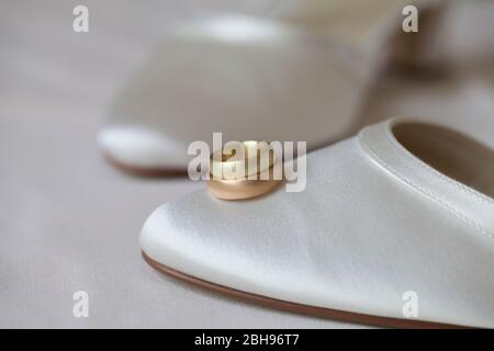 Gold and red gold wedding rings on white bridal shoe Stock Photo