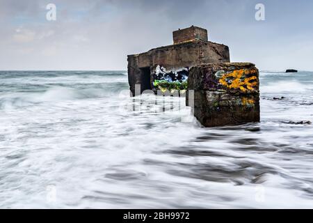 Germany, Mecklenburg-Western Pomerania, peninsula Fischland-Darß-Zingst, seaside resort Wustrow, Vorpommersche Boddenlandschaft National Park, Hohes Ufer (high bank), old bunkers with graffiti in the surf of the Baltic Sea below the cliffs at storm Stock Photo