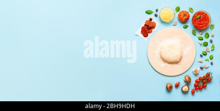 Making of pizza concept with yeast dough on a pizza stone and organic pizza ingredients. Top view of pizza ingredients and dough. Tasty pizza recipe. Stock Photo