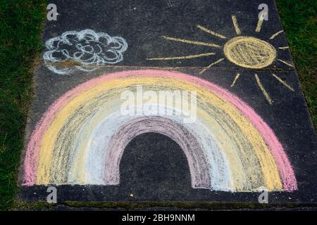 Child's drawing on the floor with colored chalks. Drawing of a rainbow, the sun and a cloud. Concept for happiness childhood and activities. Stock Photo