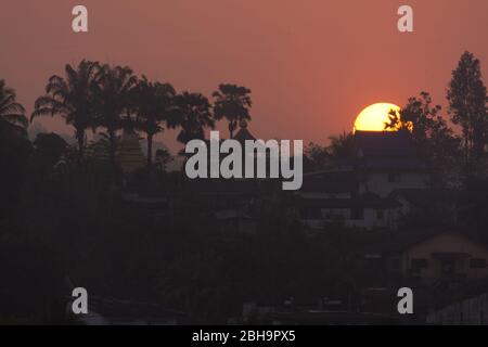 Beautiful Sunrise Behind a Temple and Palms at Laos, seen from Chiang Khong, Thailand, Asia Stock Photo