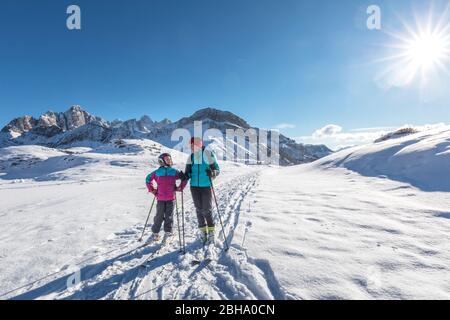 mother and daughter, family, with ski mountaineering towards the Laresei refuge, in the background the mountain ridge of Pale di San Martino, Belluno, Vento, Italy Stock Photo