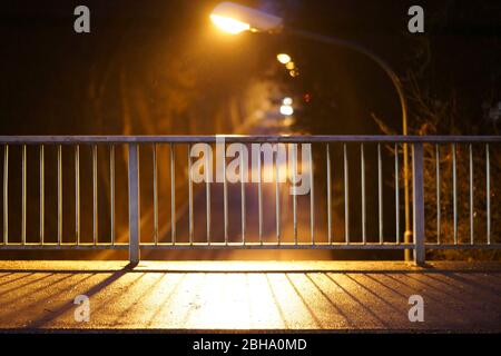 The closeup of a walkway of a bridge in the evening whose railings cast symmetrical shadows. Stock Photo