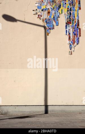 The close-up of a lantern shadow on the beige wall of a building which was decorated with broken glass. Stock Photo