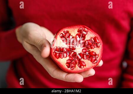 Man holding and showing cut ripe pomegranate. Pomegranate fruits are rich in sugars, tannins, vitamin C, juice is good for anemia. Stock Photo