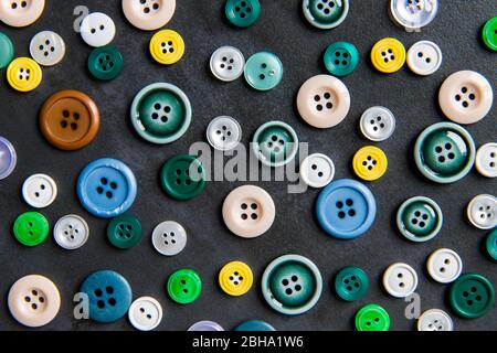 Colorful mixed sewing buttons on black background, flat lay. Top view. Stock Photo