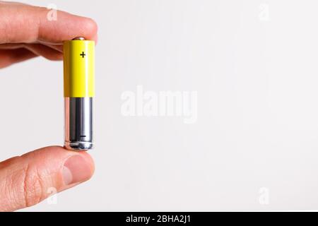 Man hand holding alkaline battery AA size, close up, isolated on white background with copy space. Stock Photo