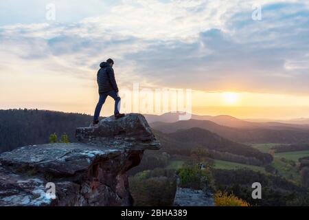 Hiker, young man, stands on vantage point, castle Drachenfels, Palatinate Forest, sunset. Stock Photo