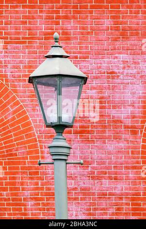 Fragment of a street lamp on a background of a red brick wall. Stock Photo