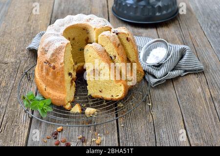 Fresh Austrian yeast ring cake with almond paste and raisins, so-called gugelhupf,  served on a shabby cooling rack Stock Photo