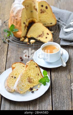 Fresh Austrian yeast ring cake with almond paste and raisins, so-called gugelhupf,  served with a cup of delicious coffee crema Stock Photo