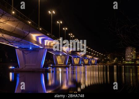 Illuminated bridge over still water with reflections Stock Photo