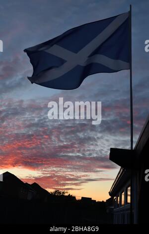 Glasgow, Scotland, UK. 24th, April, 2020. UK weather. A red sky over the west of Scotland at the end of the hottest day of the year so far in Glasgow as a Scottish flag flys over a house in the light easterly breeze. Credit. Douglas Carr/Alamy Live News Stock Photo