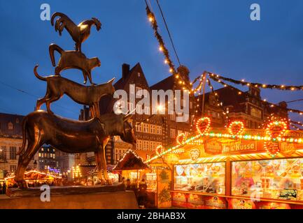 The Bremen Town Musicians and Christmas Market with Market place West side and Obernstraße at dusk, Bremen, Germany Stock Photo