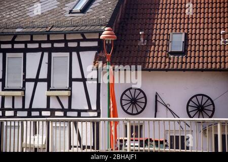 An old, nostalgic spoked wheel of a coach or a trailer and a flail hanging for decorative purposes on the wall of a farmhouse. Stock Photo