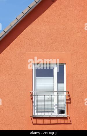 The roof edge and a window railing of a residential building cast shadows. Stock Photo