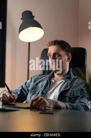Handsome Freelancer Working Remotely From Home. Artist Using Modern Devices: Computer and Digital Graphic Tablet Stock Photo