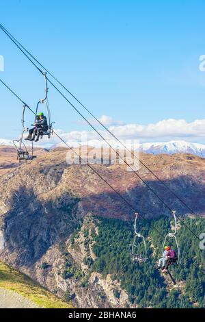 Luge riders taking lift up to top of hill, Queenstown, South Island, New Zealand, Stock Photo