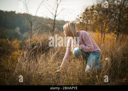 Beautiful Woman Crouching On Cliff Edge At Grass Stock Photo