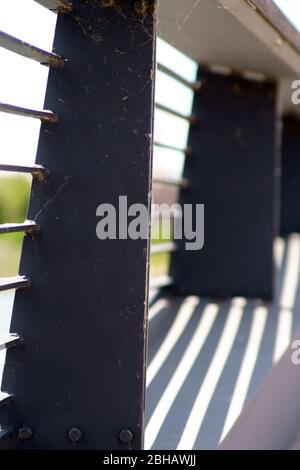 The closeup of a walkway on a bridge whose railing casts symmetrical shadows. Stock Photo