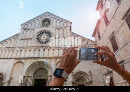 Detail of tourist hand taking pictures of the Cathedral of St Anastasia, Zadar, Dalmatia, Croatia Stock Photo