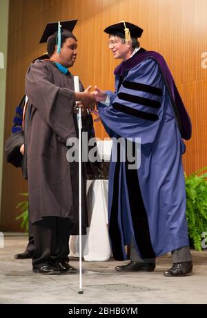 Austin , Texas - May 22 , 2009 A blind student using a white cane participates in graduation ceremony at the Lyndon Baines Johnson (LBJ) School of Public Affairs. Approximately 108 students received their Masters or PhD's in public policy studies through the school at the University of Texas at Austin. Keynote speaker James Steinberg (r) helps hand out diplomas.    ©Bob Daemmrich Stock Photo