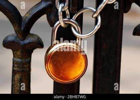 padlock and strong steel chain wrapped around the metal entrance gate as a part of security and safety Stock Photo