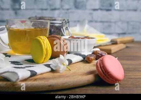 A mug of mint tea with cookies macaron, on a wooden board and finnick on wooden cutting board Stock Photo